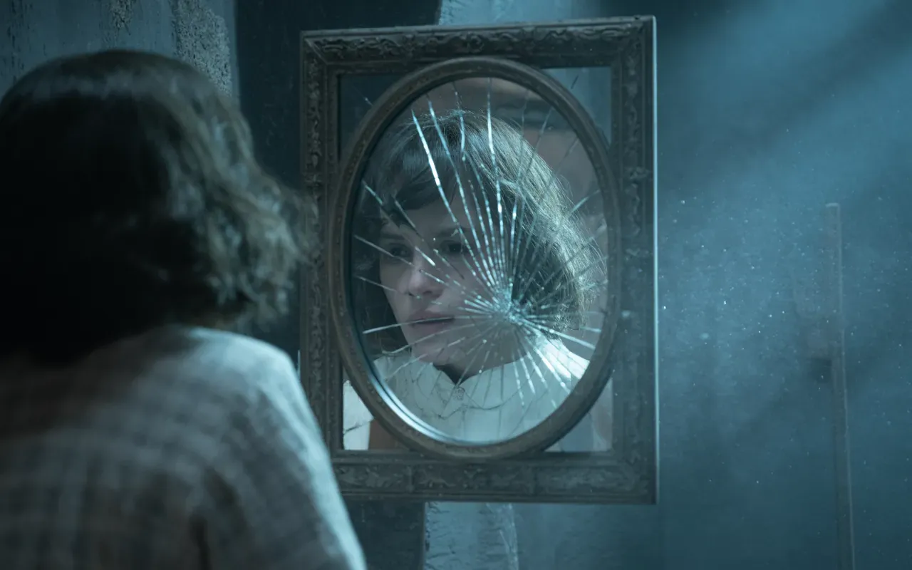 A cracked antique mirror in a dimly lit room reflecting a distorted face in dreamlike blue light
