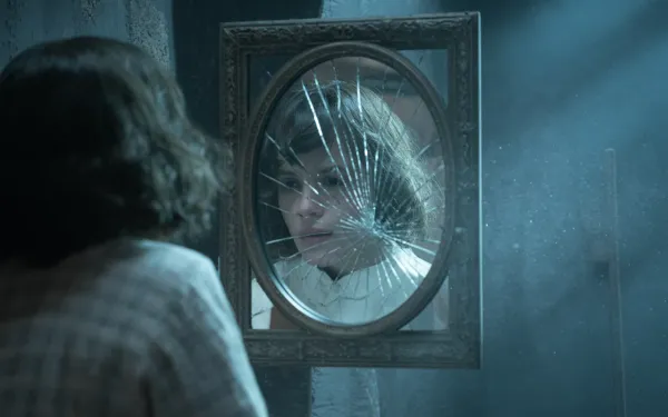 A cracked antique mirror in a dimly lit room reflecting a distorted face in dreamlike blue light